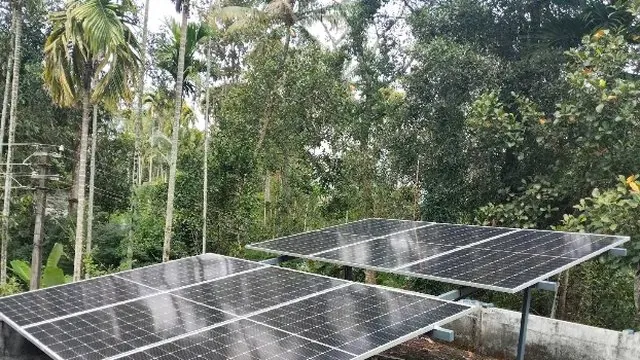 Two solar arrays on a flat concrete terrace in Pappinivattom, Thrissur, angled south and raised on frames with airflow underneath.